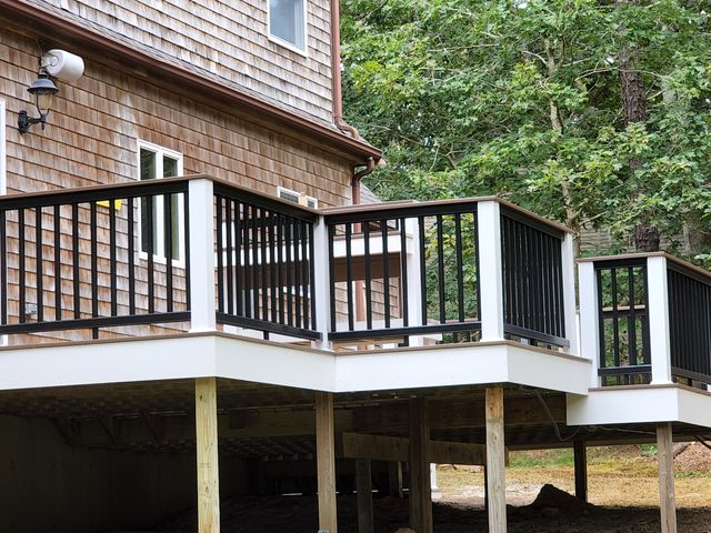 Deck with black railings along the side of a shingled house