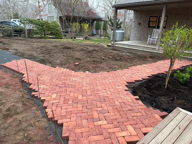 Herringbone brick path curving past a porch